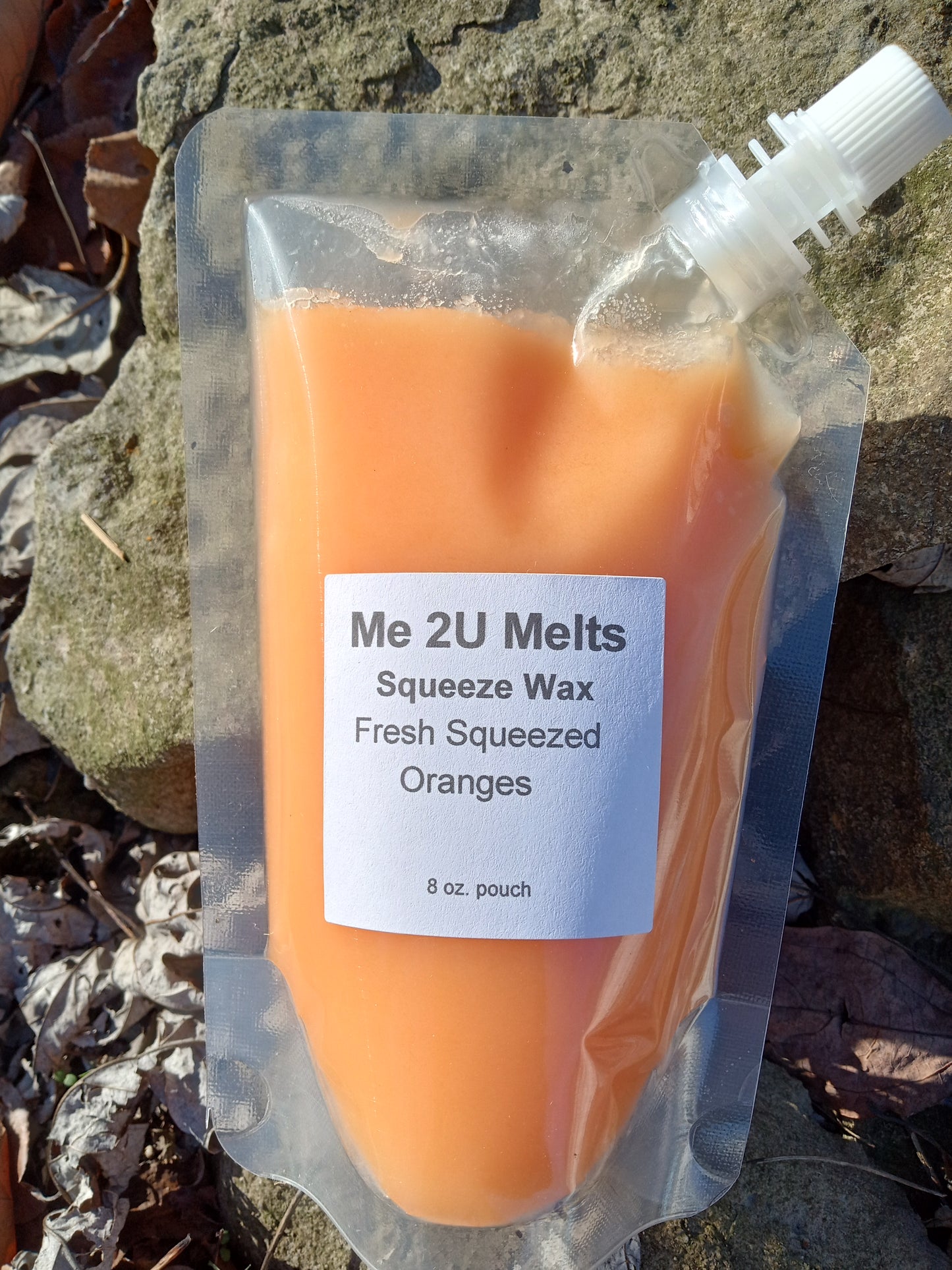 Orange wax product in a clear packaging with a label on a rocky surface